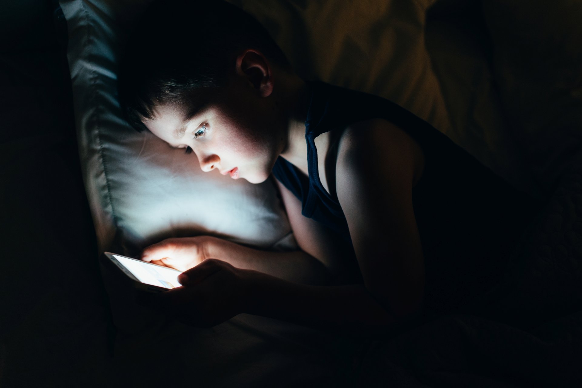 Boy on cellphone in bed.