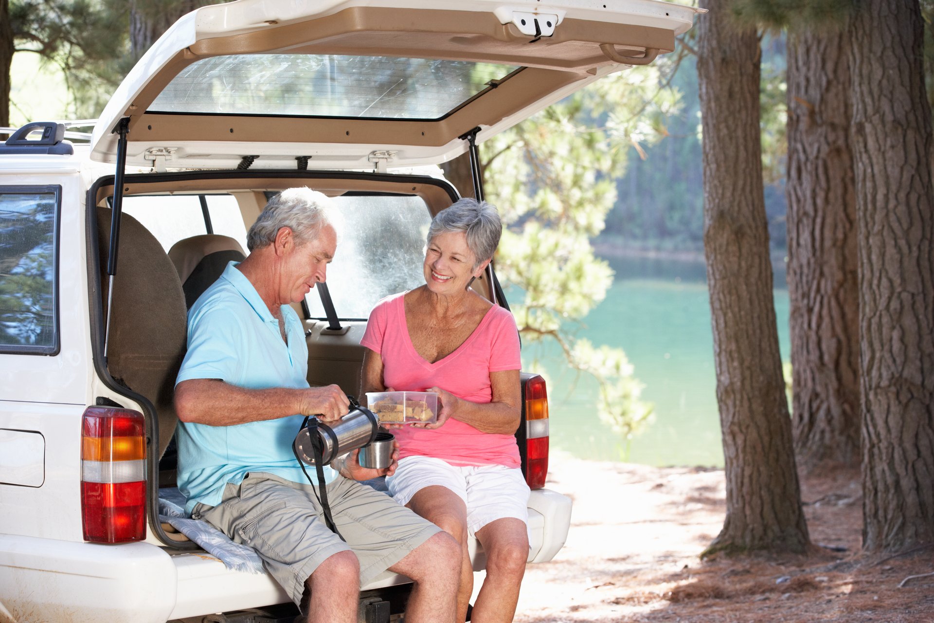 A senior couple sits in their car while on a camping trip