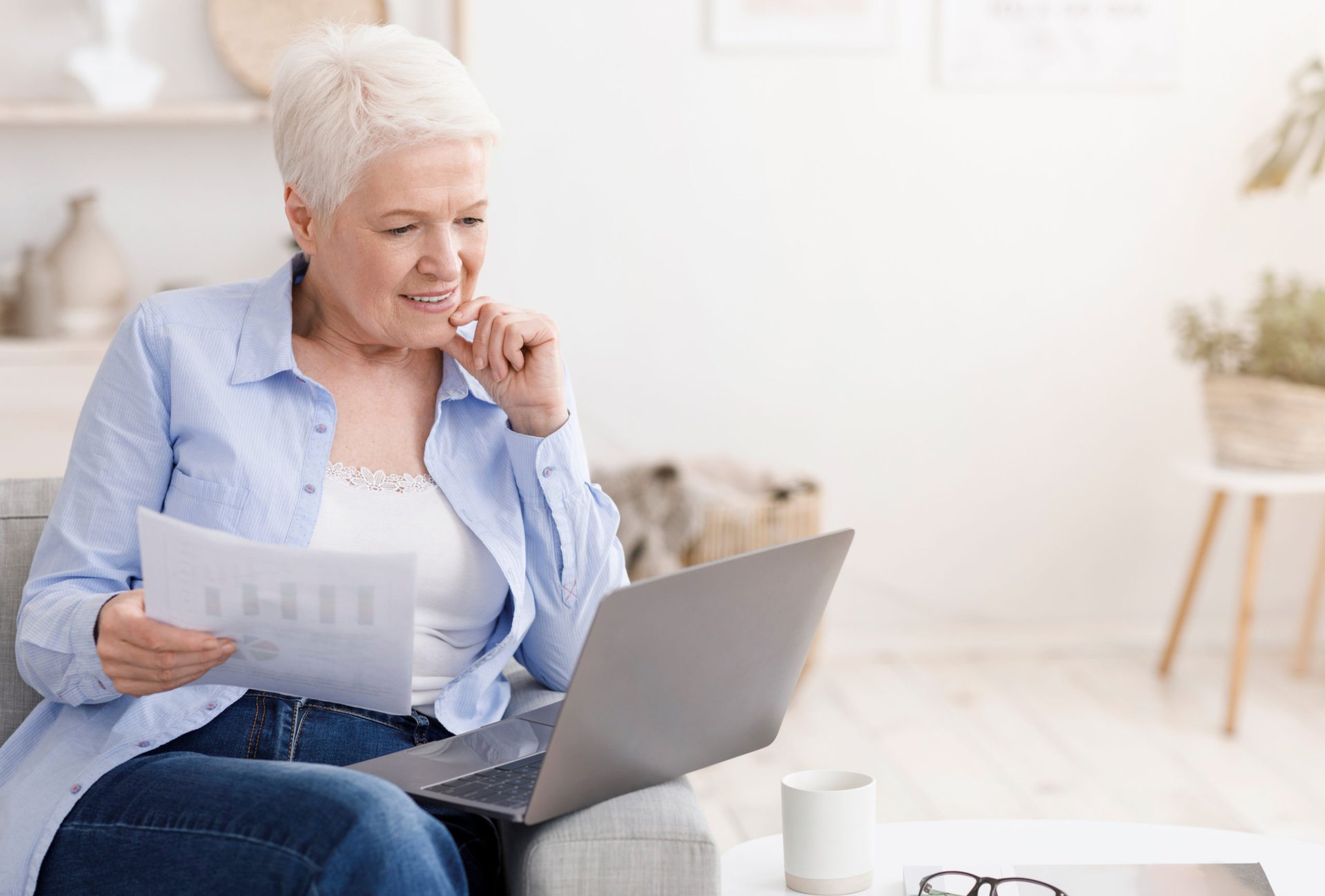senior woman white gray hair couch crunching numbers computer