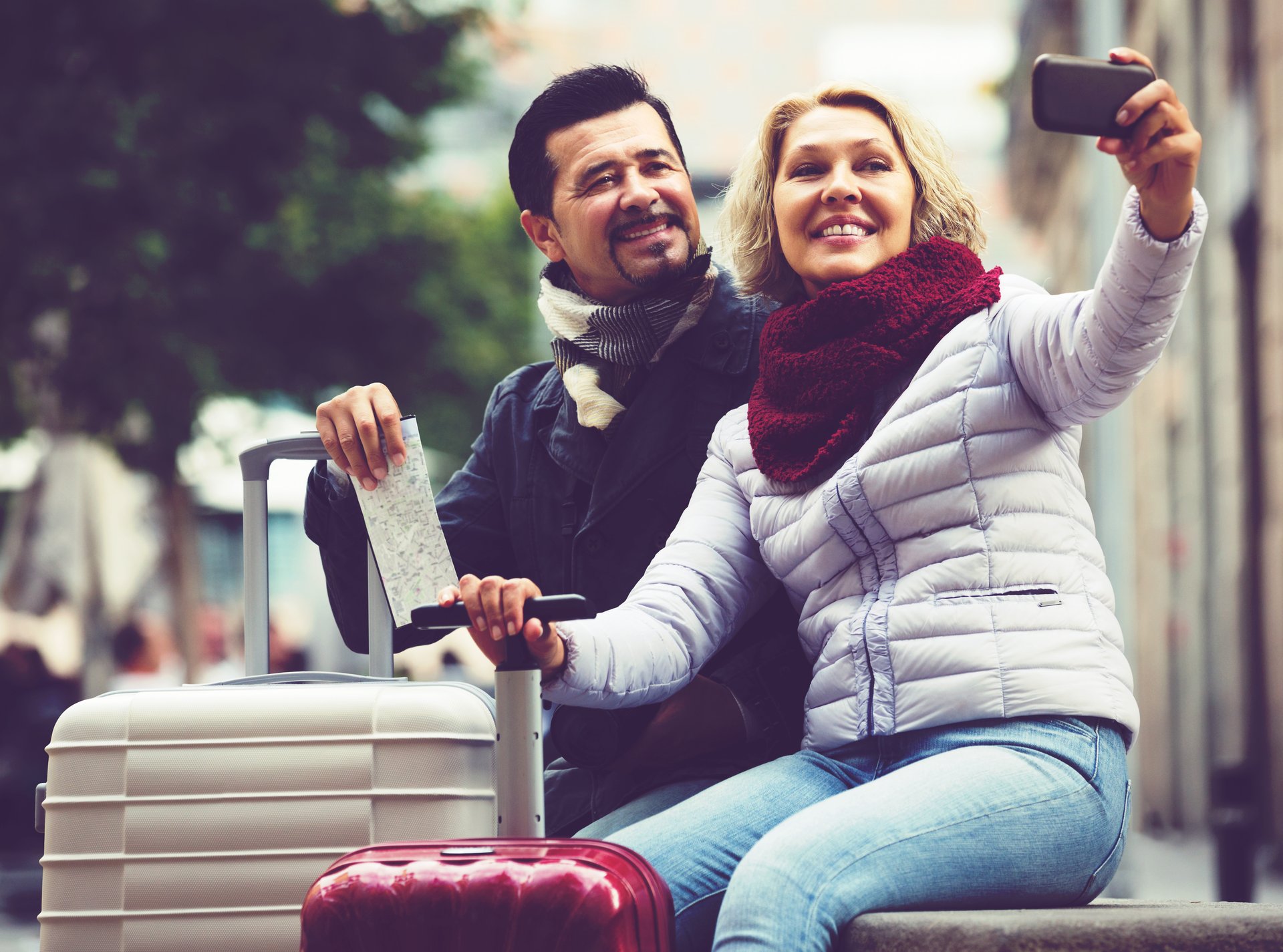 Couple with suitcases taking a selfie.