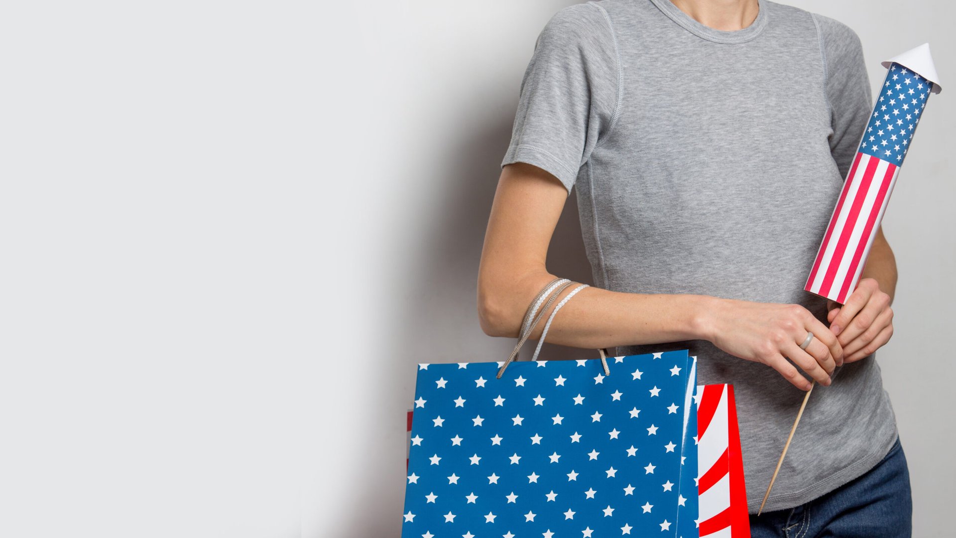 Patriotic woman with a firework and shopping bags in the colors of the American flag