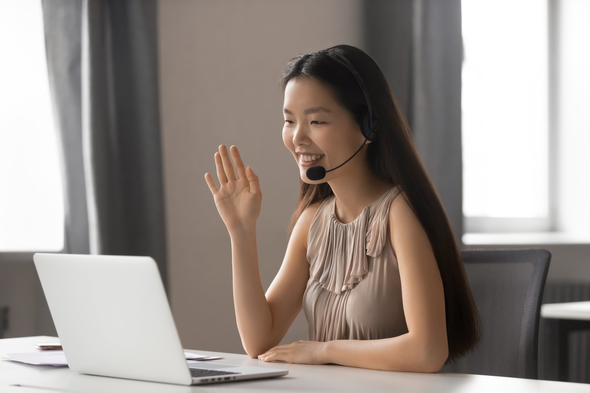 A young Asian woman wears a headset for on online meeting