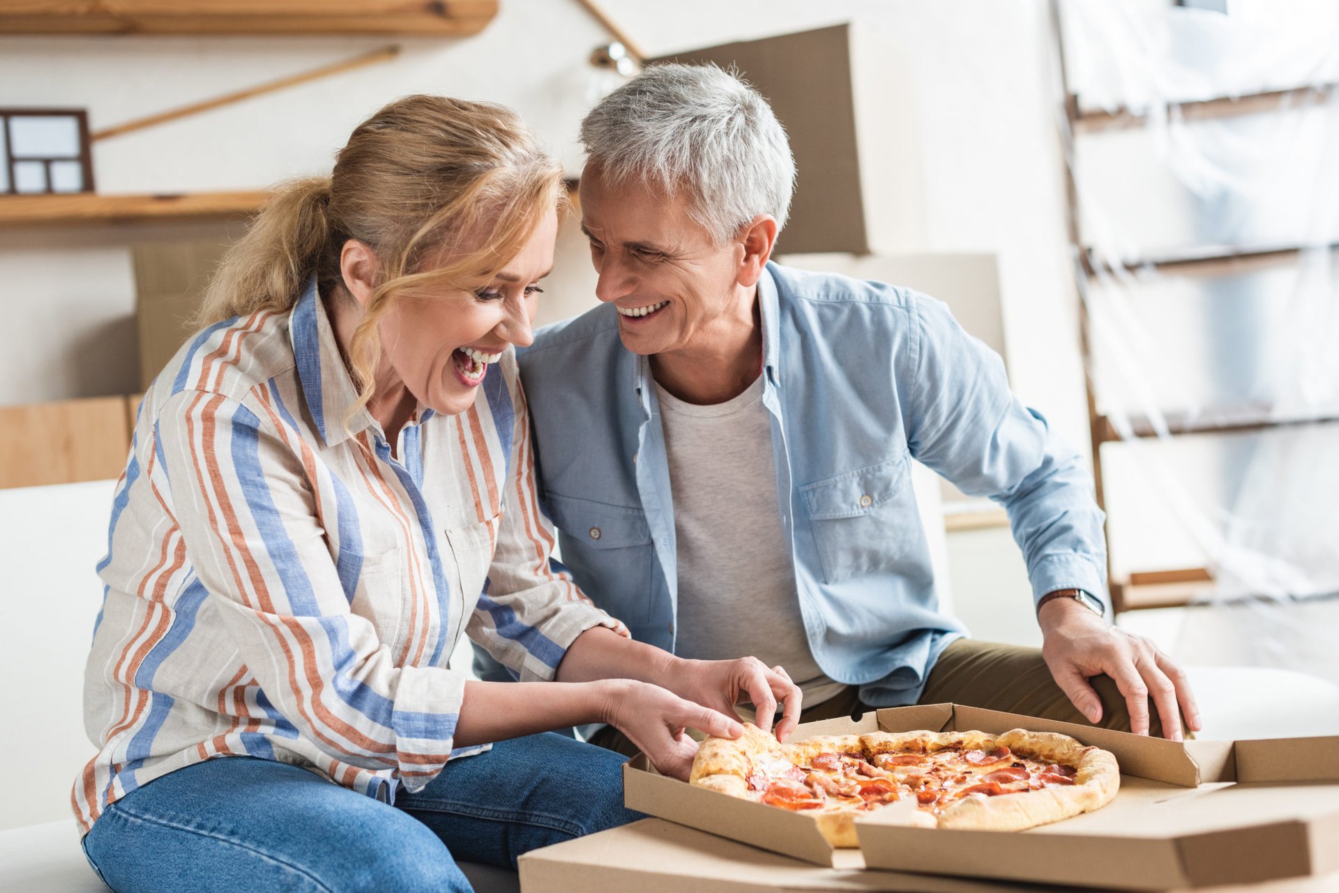 An older couple eats pizza at home