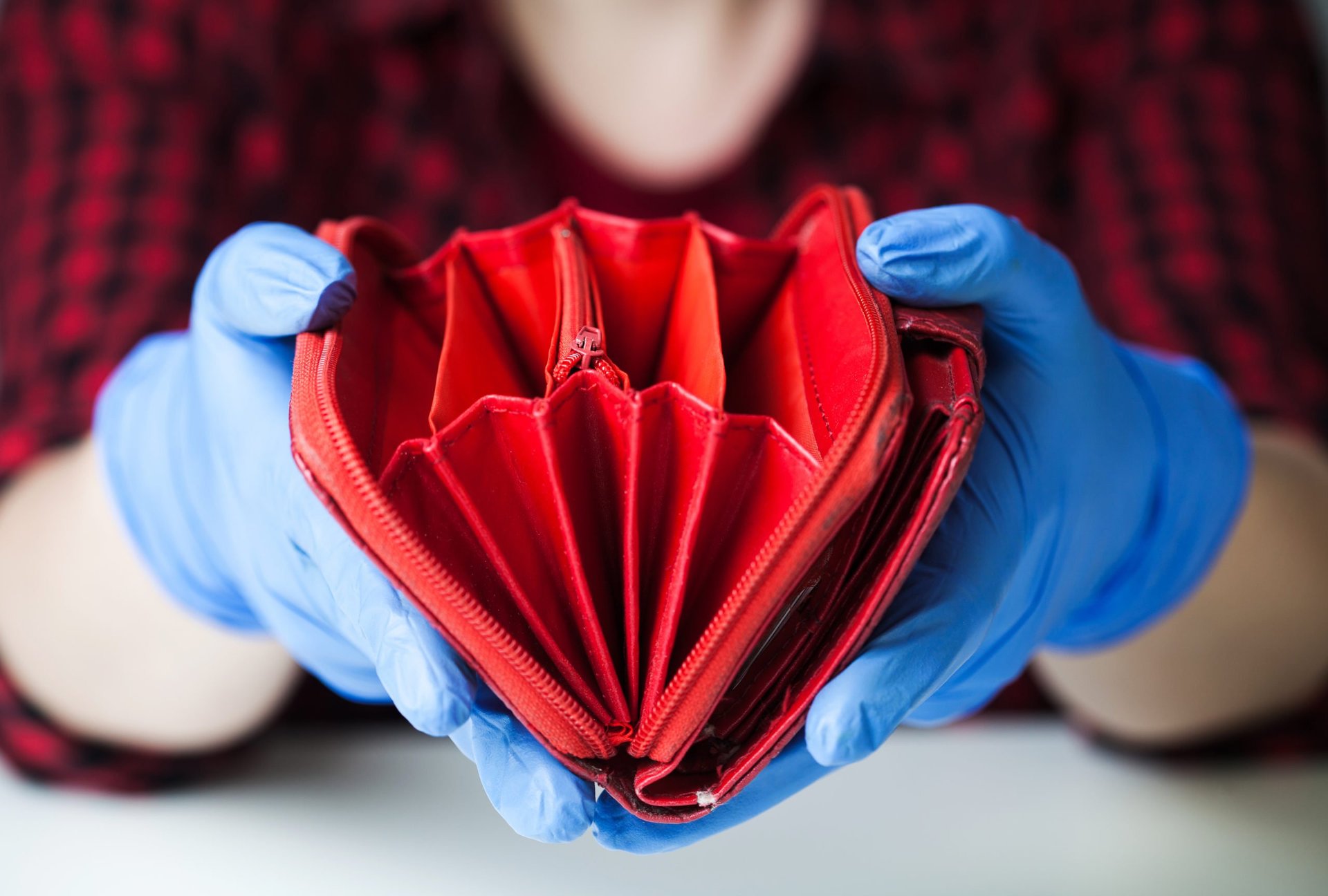 a woman in medical gloves holds an empty wallet