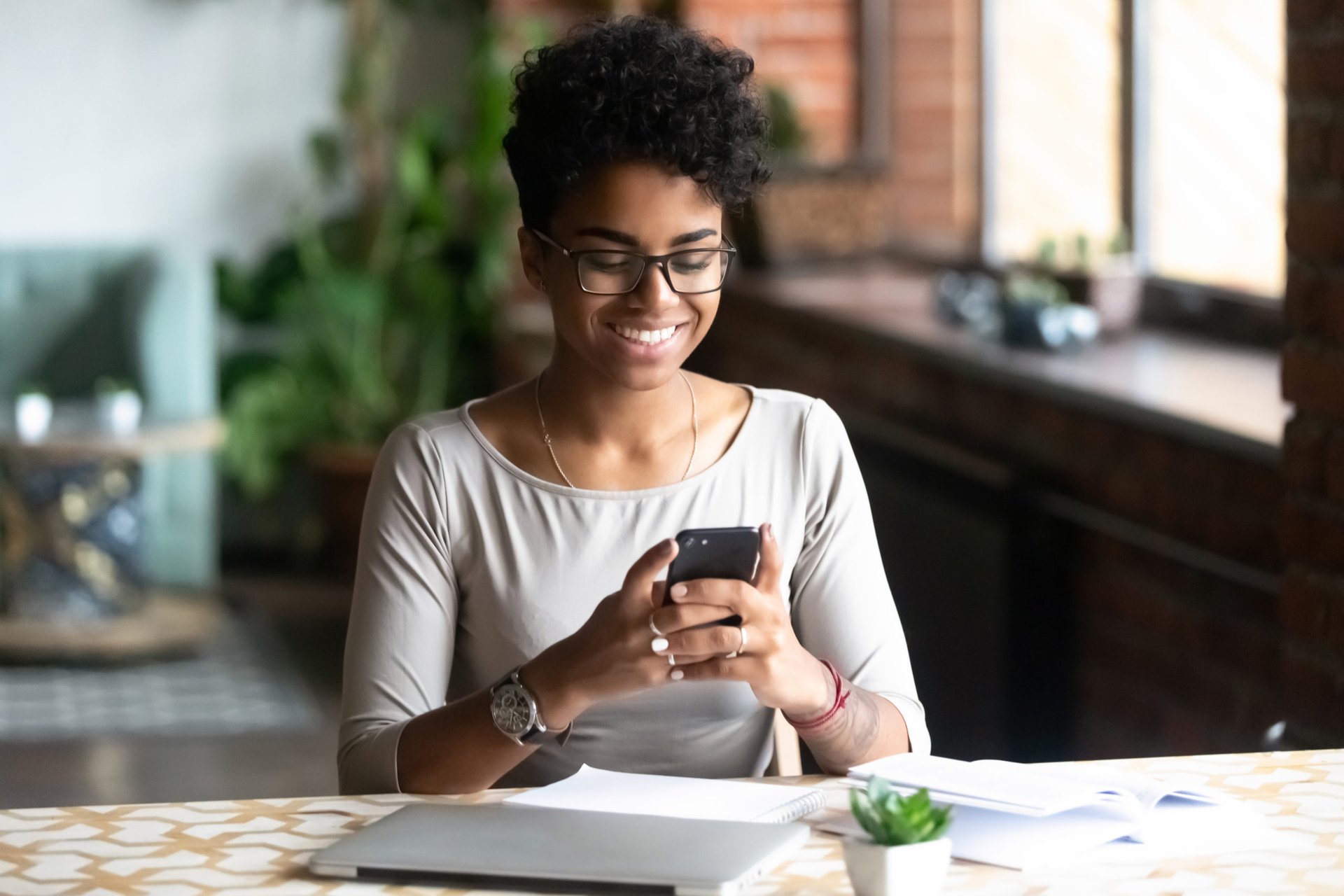 A young woman is happy using her phone at the table because she has the best phone plan