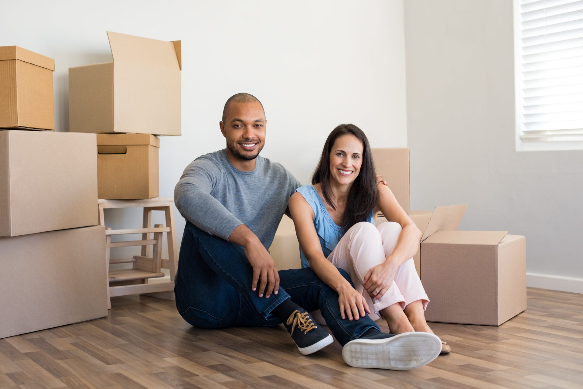 A happy couple with boxes sitting on the floor of their new home