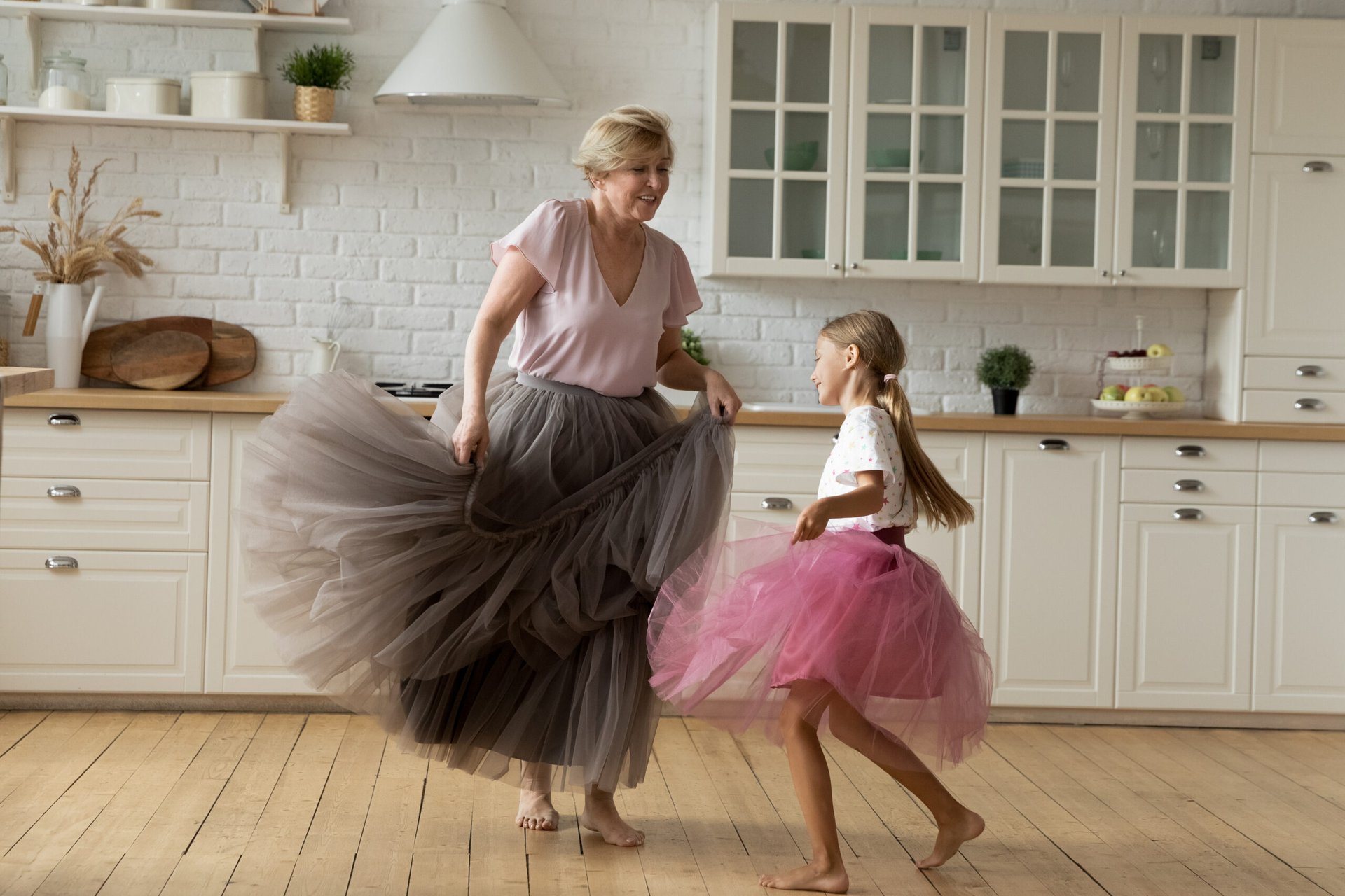 Grandma and granddaughter dancing in a kitchen