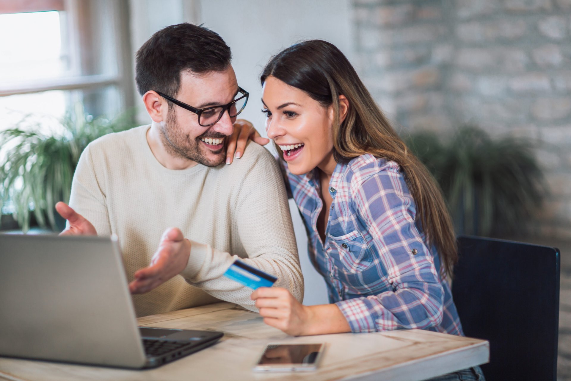 Happy couple using credit card to shop online
