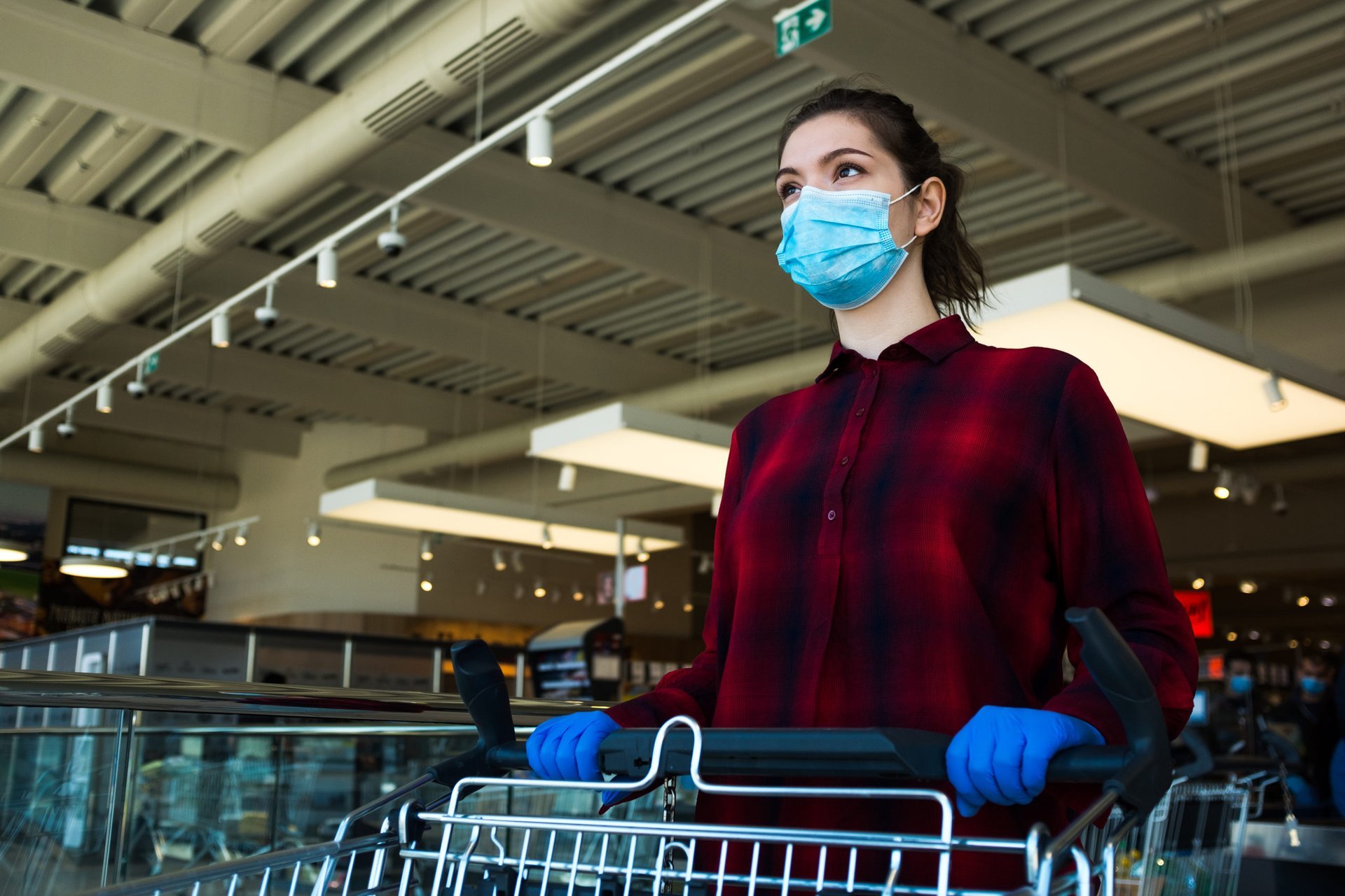 A woman in a mask pushing a grocery cart