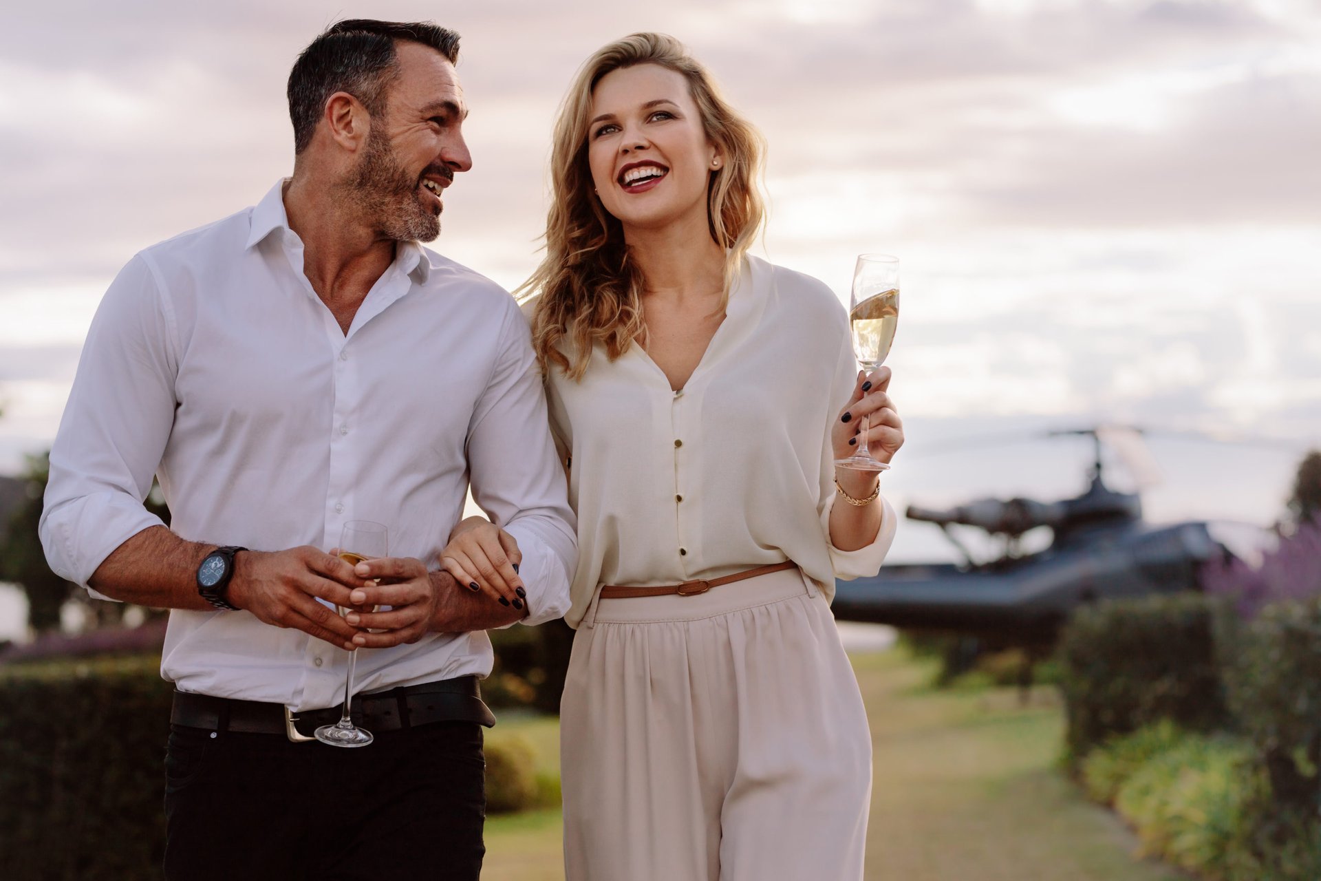 Affluent couple, sipping champagne, smiling and looking jolly
