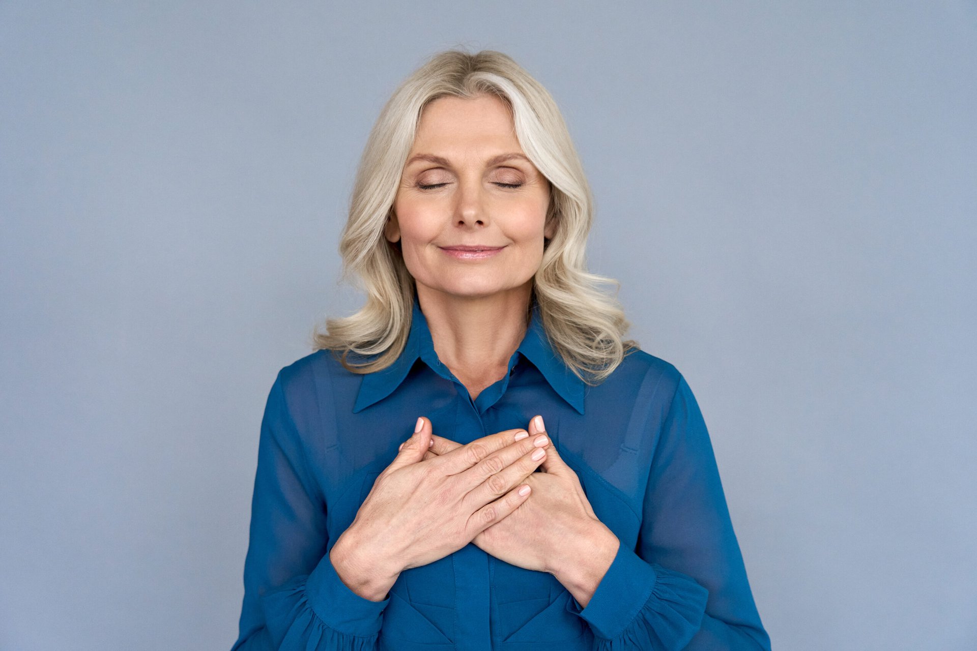 Happy older woman smiling and holding her hands over her heart