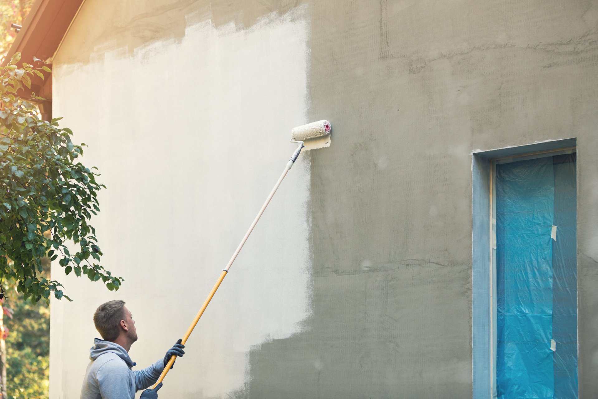 Worker painting the exterior of a home white