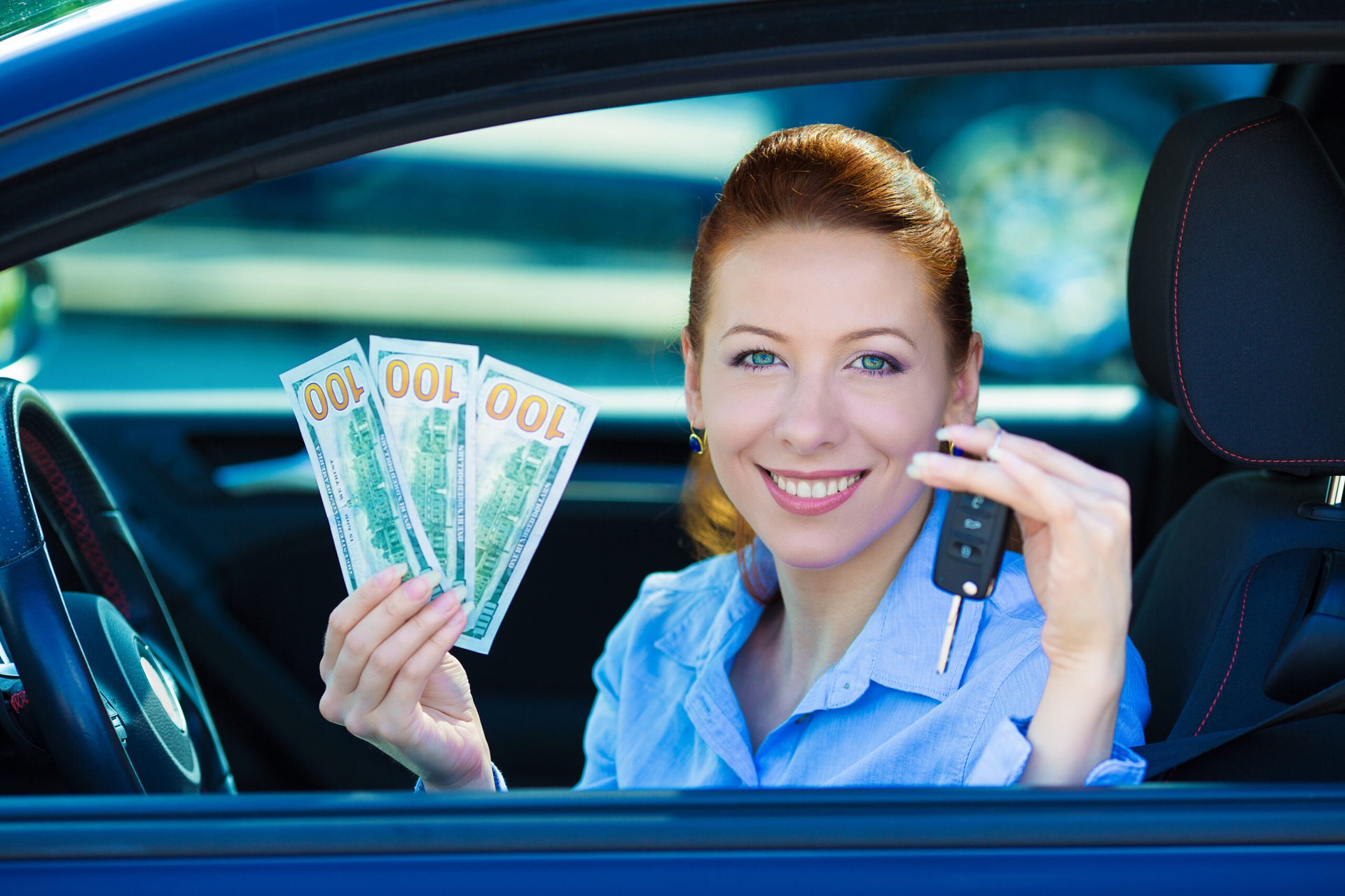 Woman in a car holding up money
