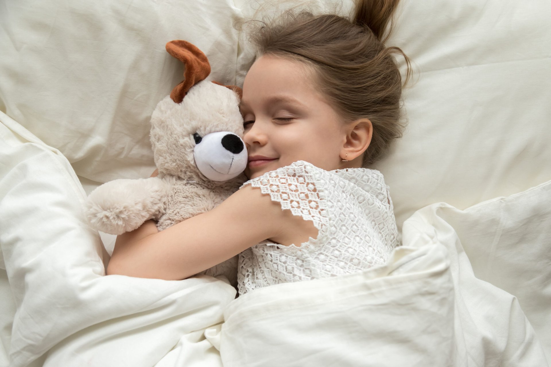 Little girl in bed with a teddy bear