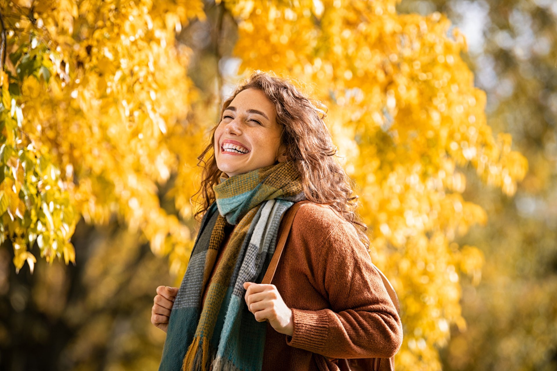 Woman smiling with fall leaves in the background