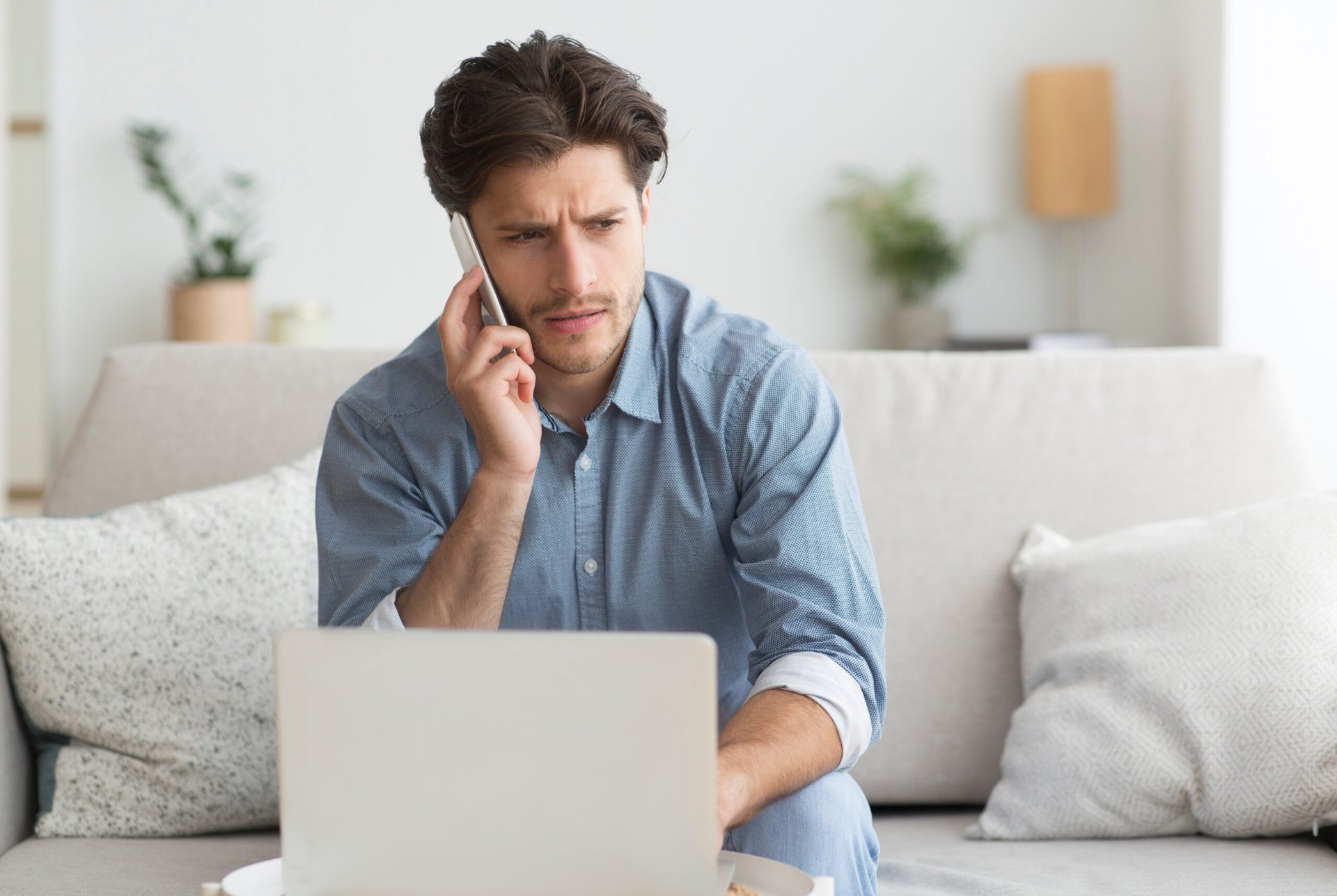 Man frustrated on the phone at laptop