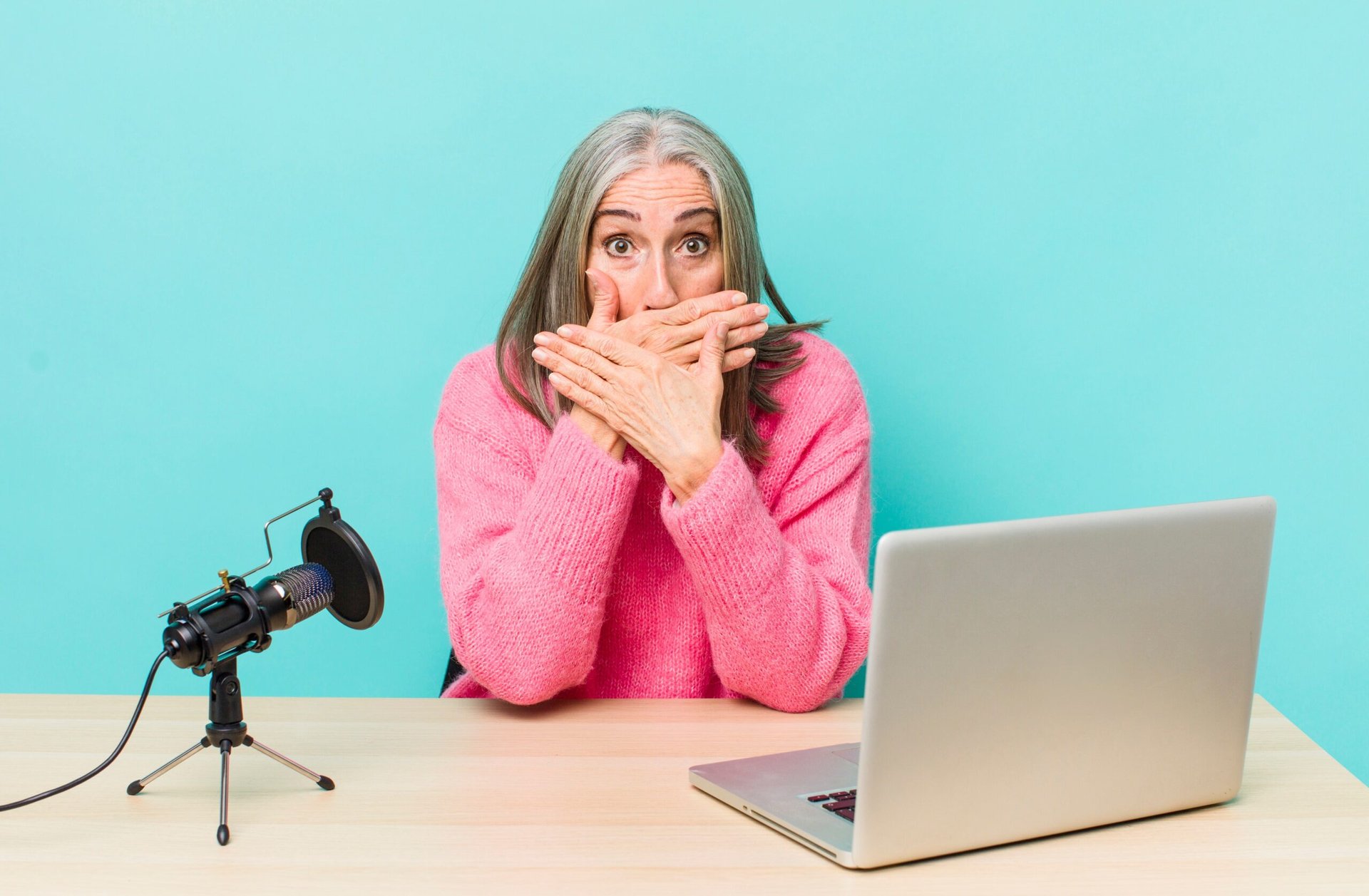 Older woman covering her mouth because she made a mistake during an online job interview for remote work on her laptop