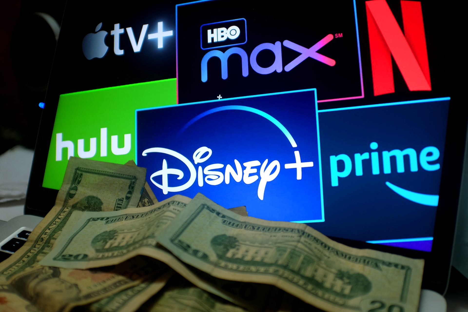 Pile of cash money in front of a TV with several streaming service subscriptions