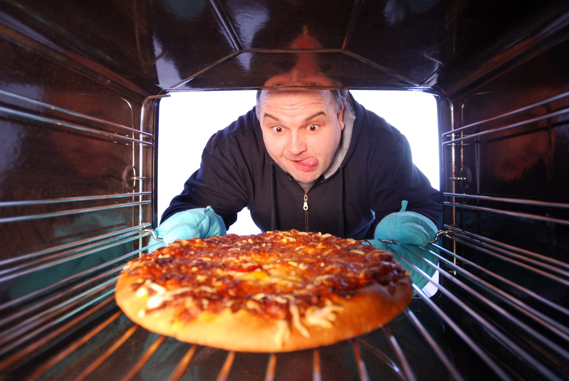 Man pulling a frozen pizza from the oven