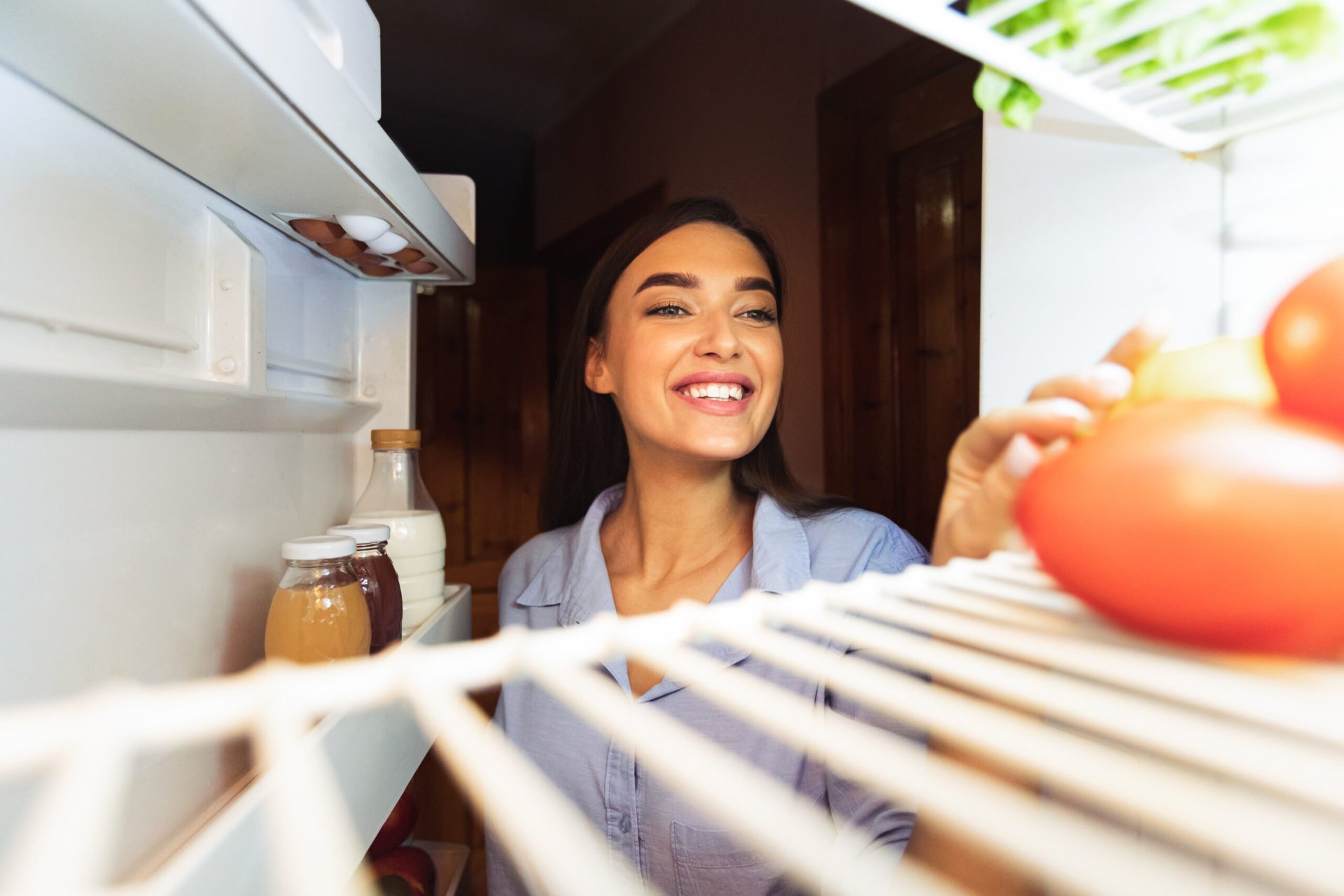Happy woman looking into a refrigerator