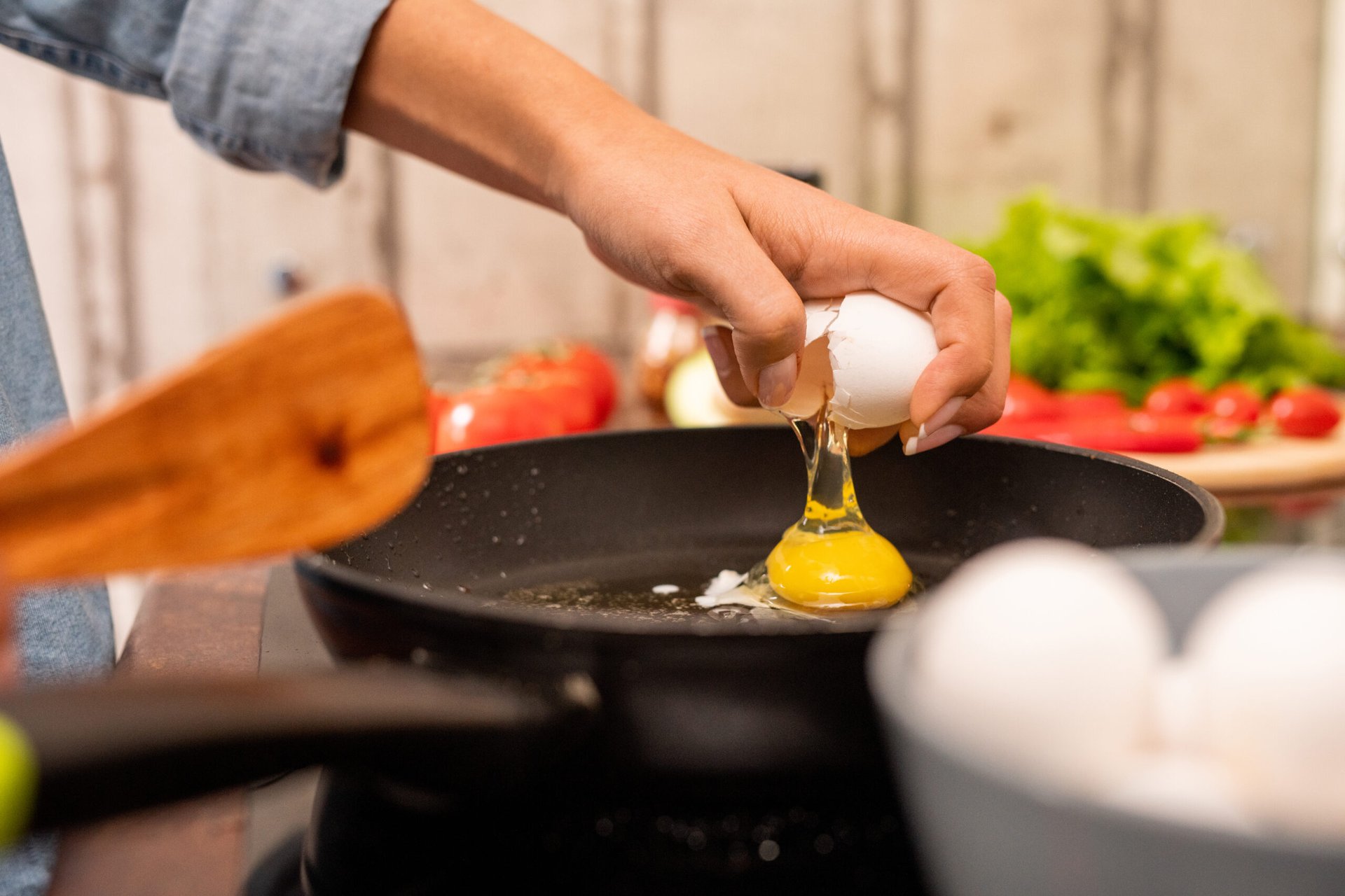 Cracking an egg into the frying pan in the kitchen cooking a meal