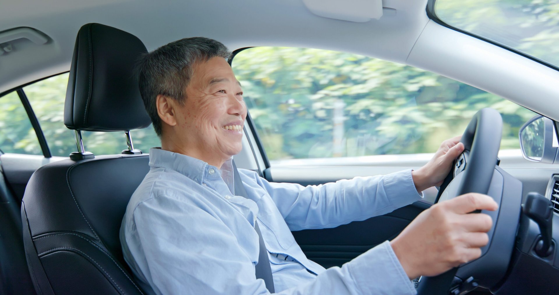 Smiling senior driver in a car on the highway driving for Uber or carrying a passenger