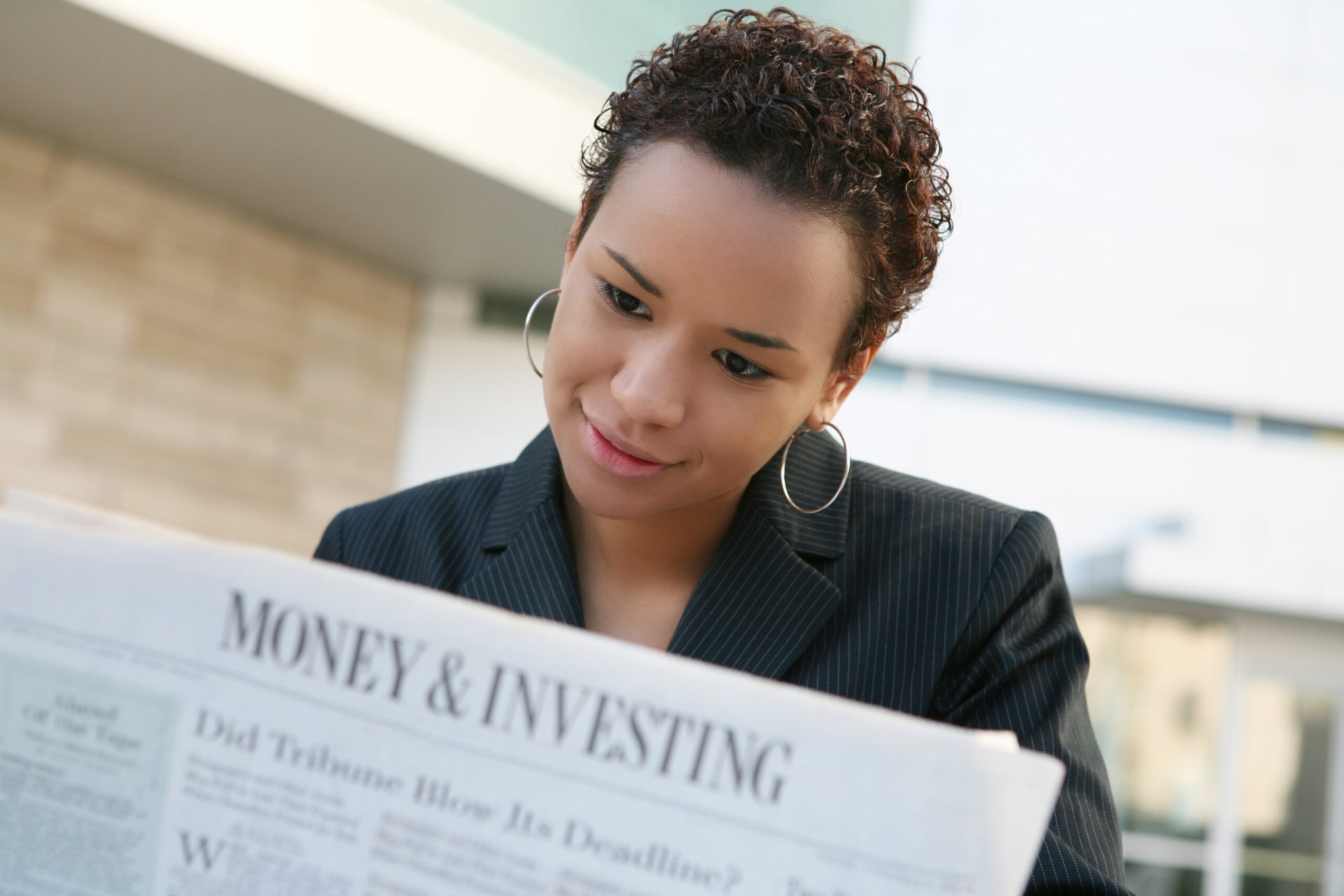 Woman reading about money and investing in the newspaper