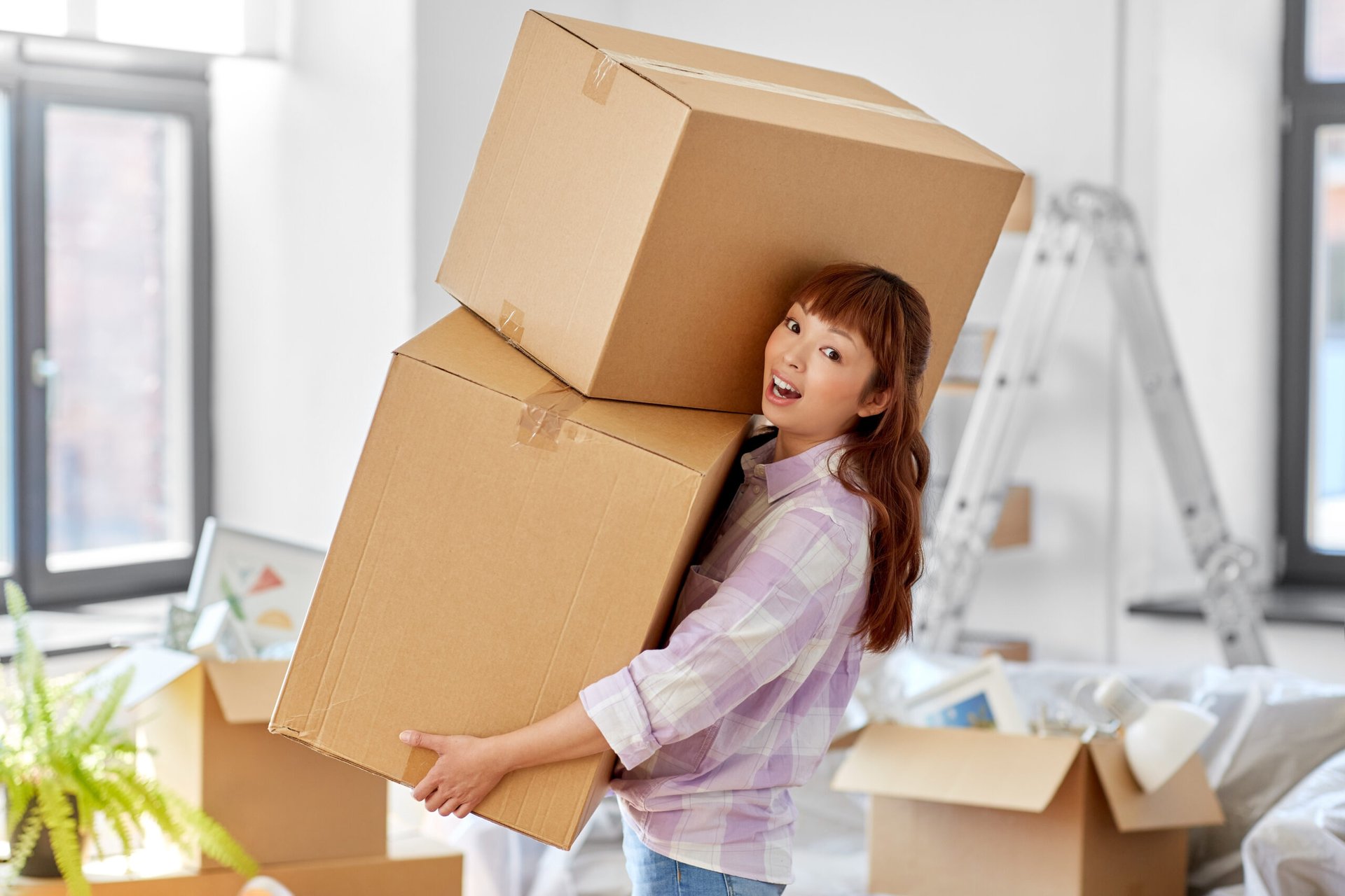 Excited woman carrying moving boxes to her new home