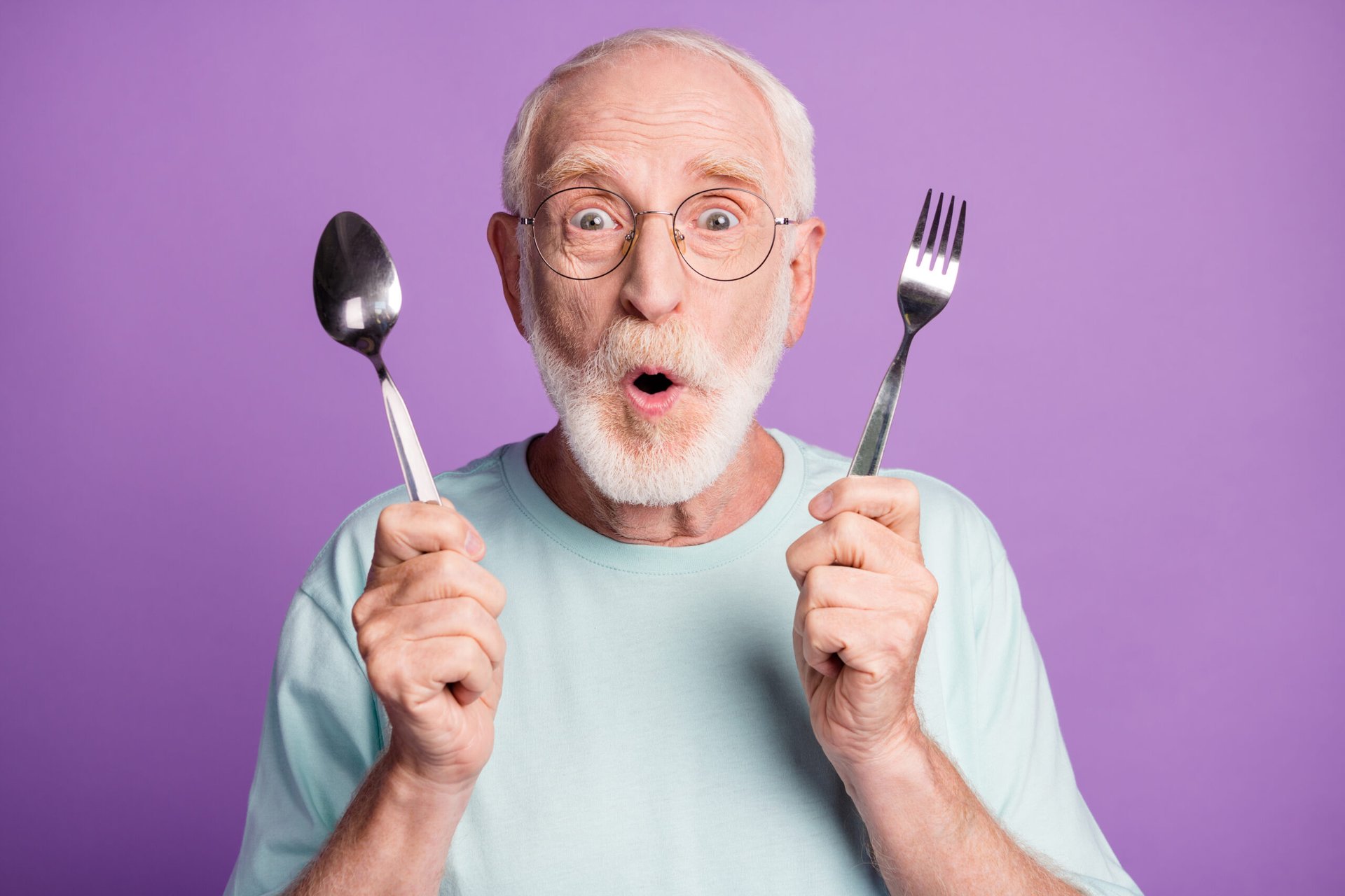 Surprised senior man with a fork and spoon