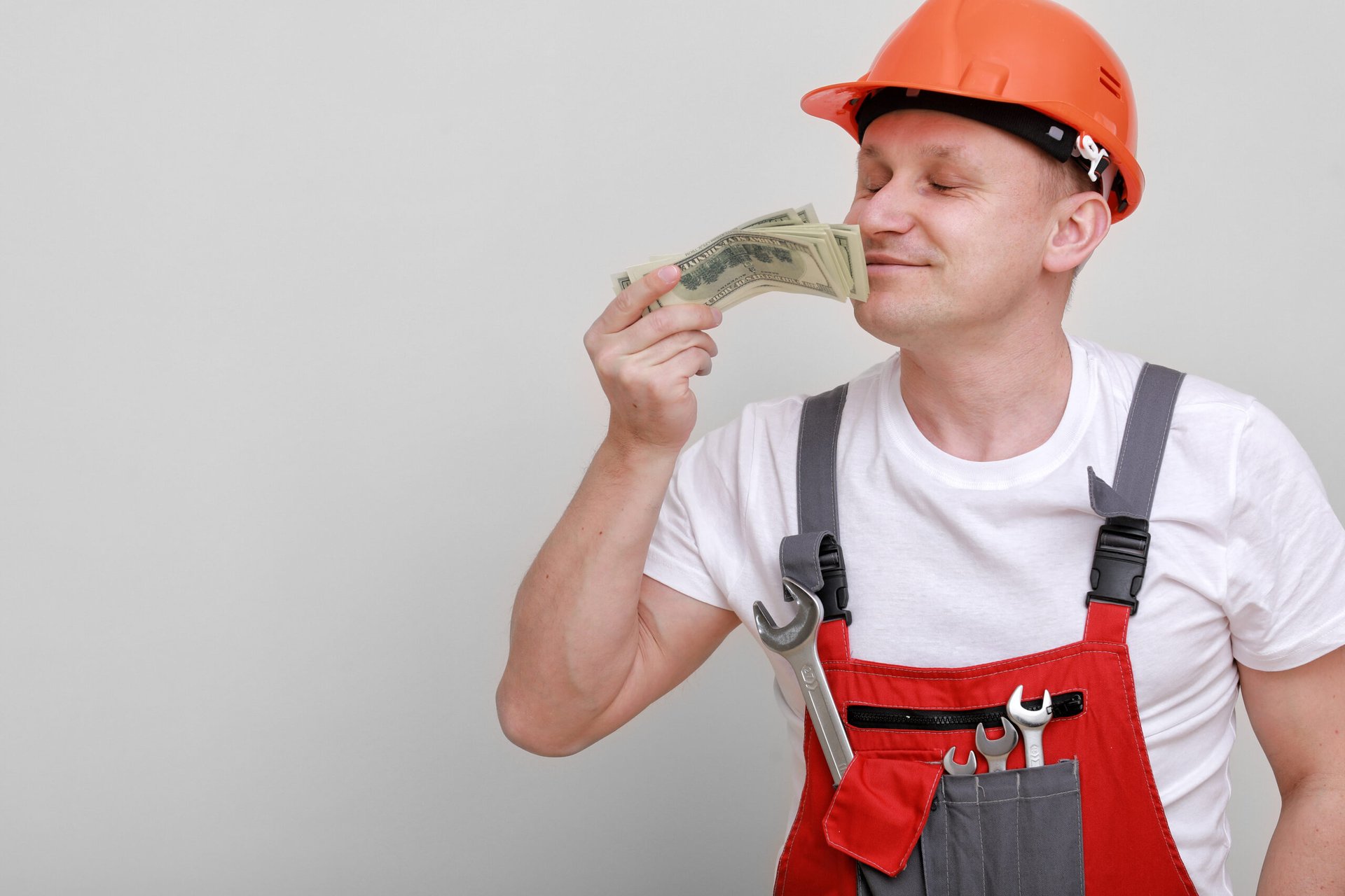 Happy construction worker sniffing money and getting a whiff of a raise or payday