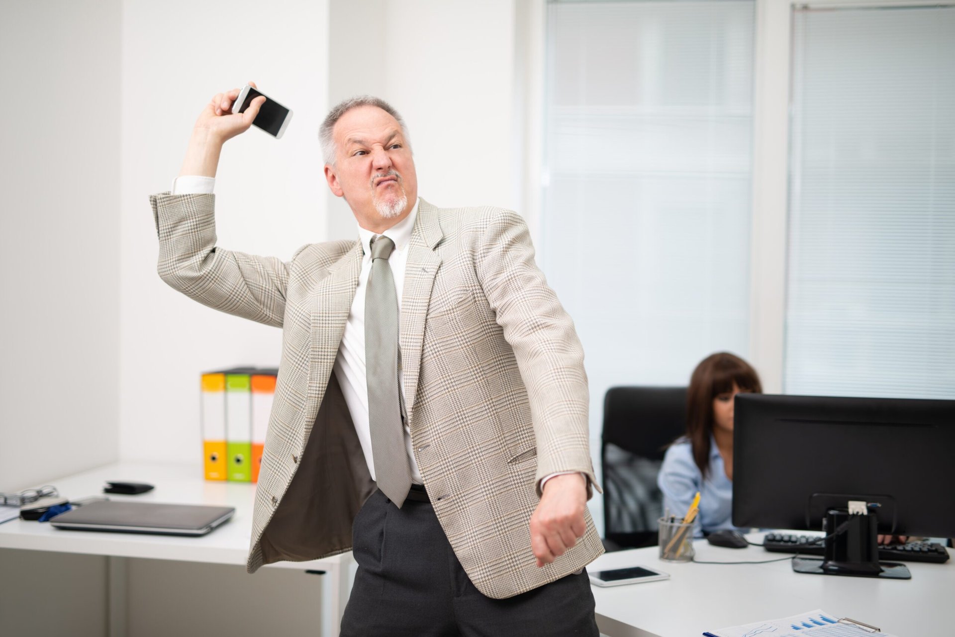Angry man in the office throwing his phone