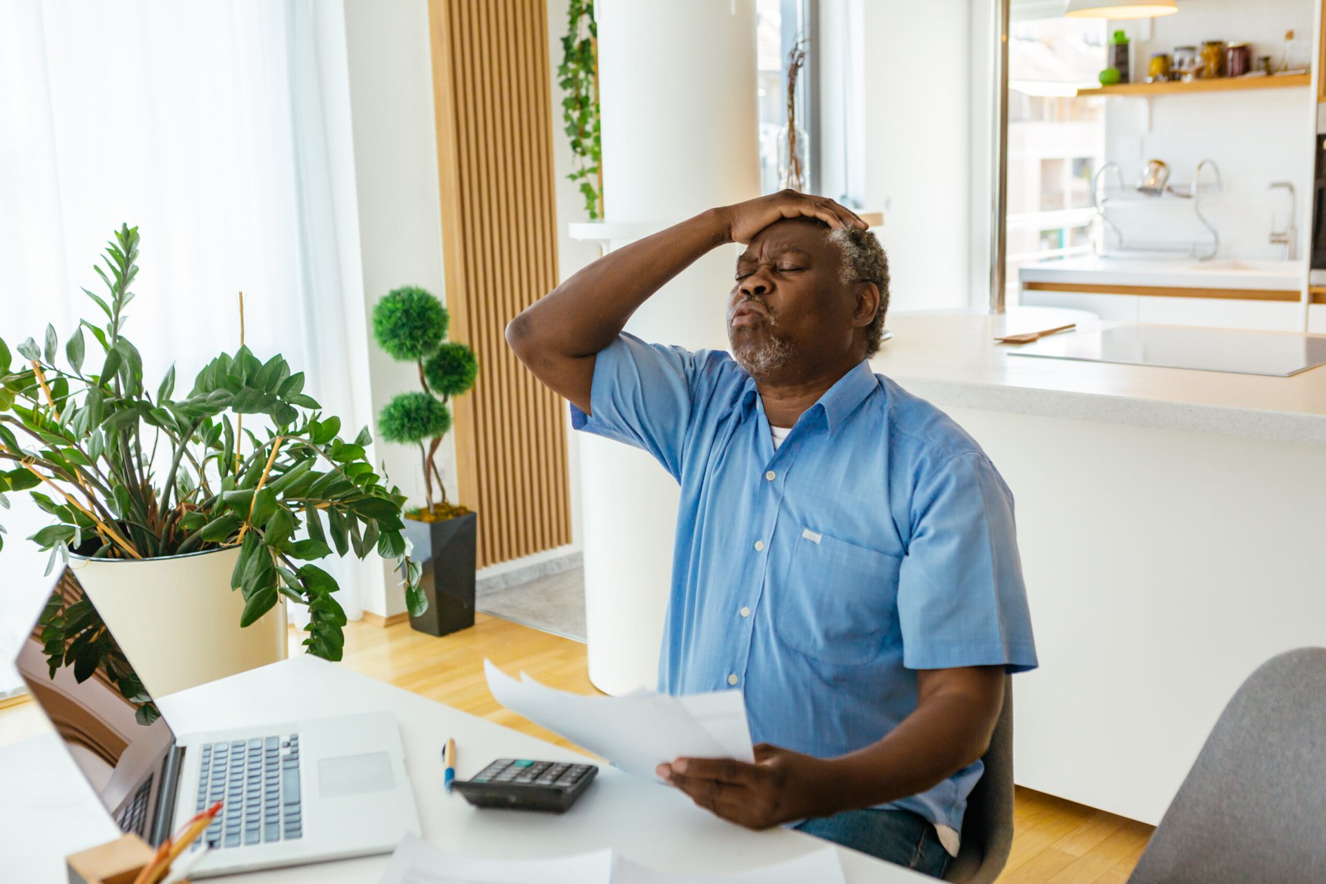 Stressed senior man paying bills sitting in his home office
