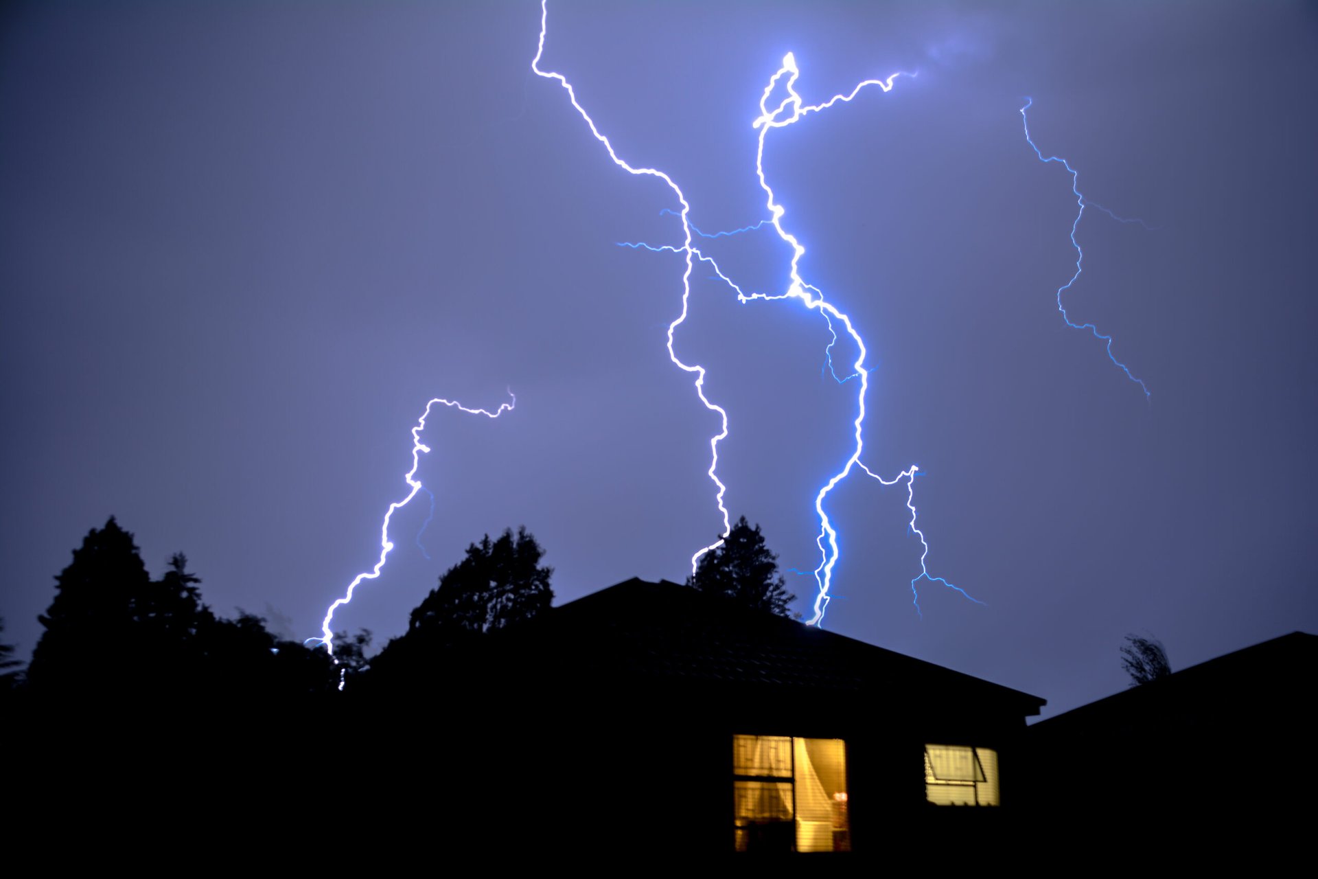 Lightning above a house during a thunderstorm