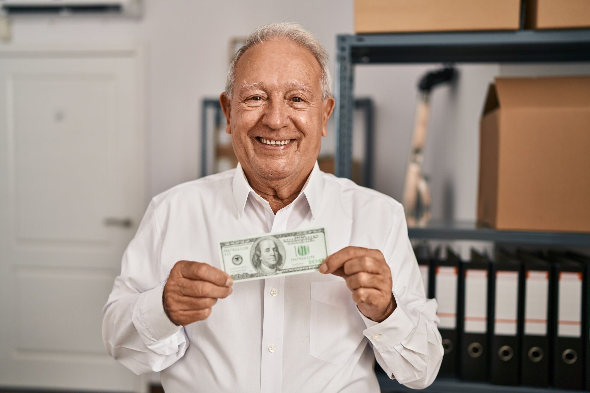 Senior man holding a $100 bill