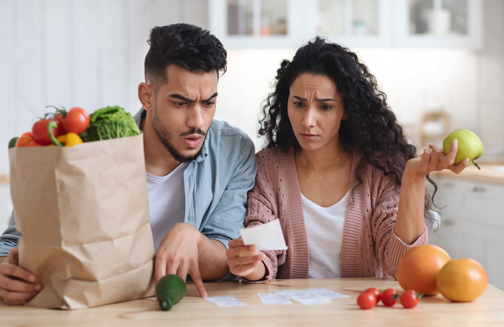 Shocked couple looks at their grocery bill