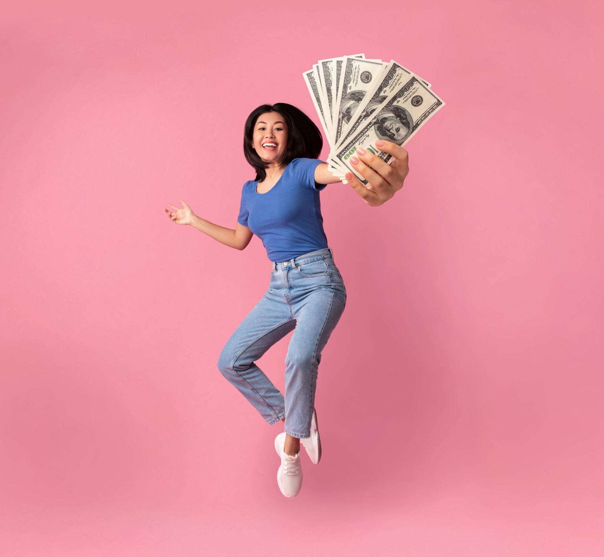 Jumping woman with a handful of cash