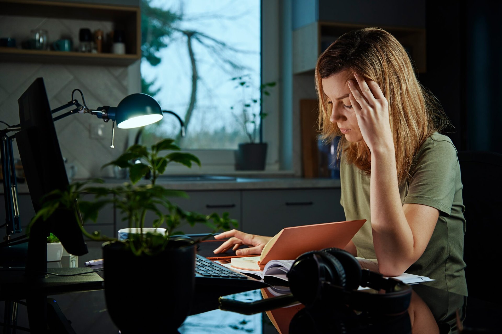 Stressed woman working from home late into the evening and suffering from burnout at her computer desk