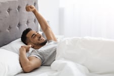 Man stretching in bed
