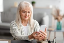 Frustrated older woman who is a senior or retired woman looking at her smartphone in consternation