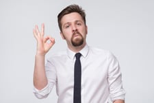 Businessman giving grudging respect or surprised approval with an OK hand symbol