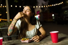 Happy woman with tattoo eating a taco outdoors