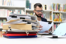 Man at desk with piles of paperwork