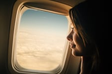 A passenger looking out the window of an airplane.