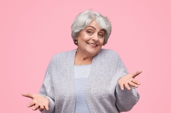 Senior woman retiree shrugging and smiling