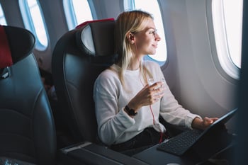 A woman using her computer and headphones during a flight.