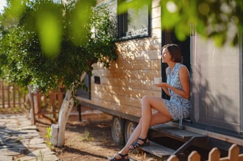 A woman drinking coffee in the morning in front of tiny home.