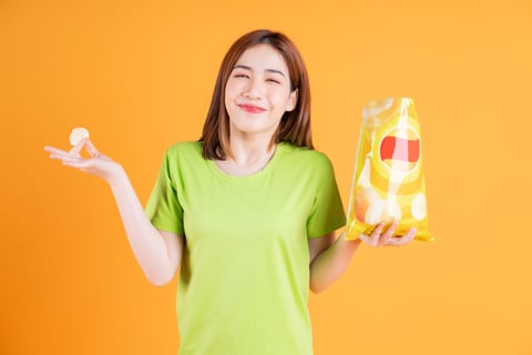 A woman holding a bag of potato chips.