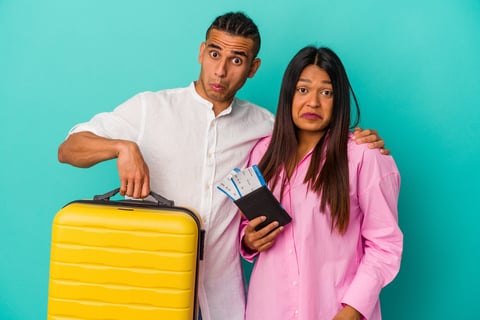 Confused couple holding luggage preparing for flight on vacation