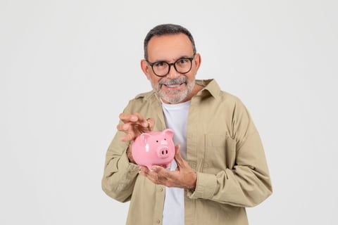 Older man putting money in piggy bank