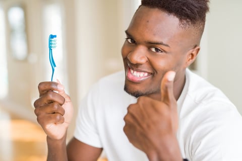 Smiling man about to brush his teeth